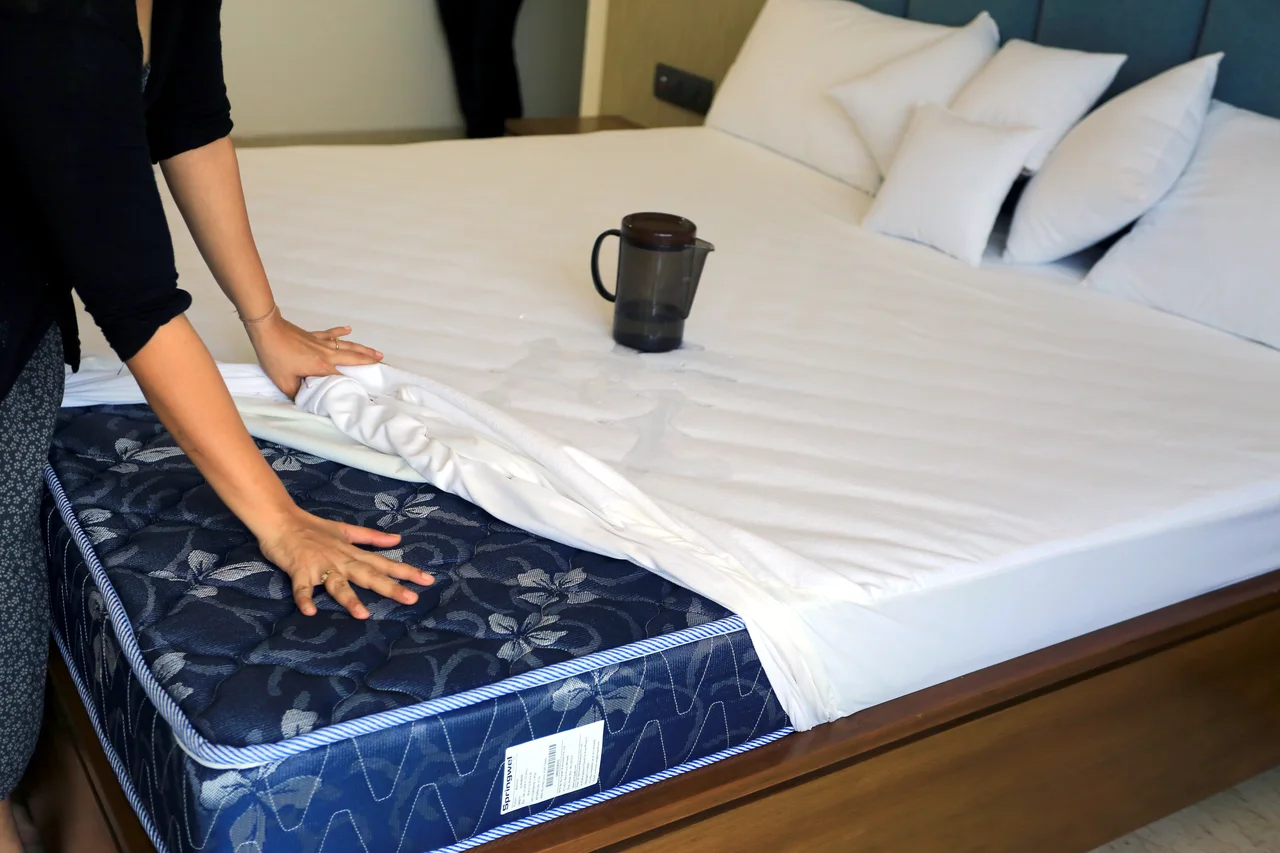 White bedding lifted at the corner to reveal the mattress underneath