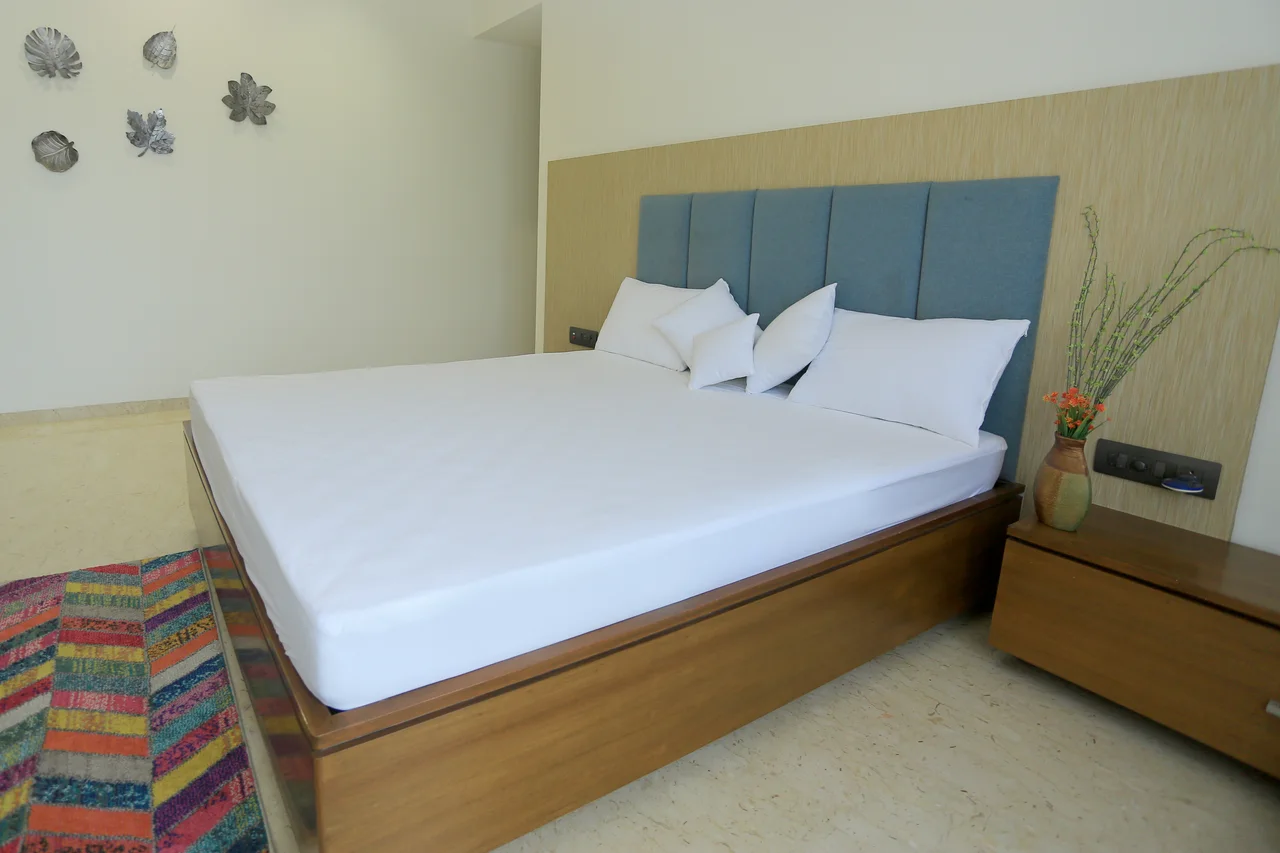 White fitted bedding with a blue upholstered headboard